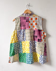Colorful patchwork top on a hanger against a white background
