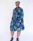 Model wearing dress with blue and grey gear graphic print.