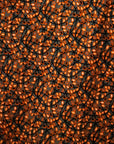 Close up display of grey dress with black and orange vine design, fabric.