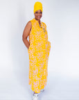 Model wearing yellow sleeveless dress with abstract pink print.
