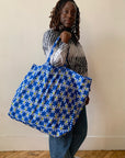 Person holding a blue tote bag with floral pattern against a plain background