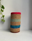 Display of hot pink, beige, blue and sage green striped vase