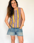 The model is wearing olive-yellow, blue, orange and white geometric printed tank