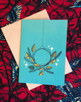 Turquoise colored greeting card with green and yellow wreath