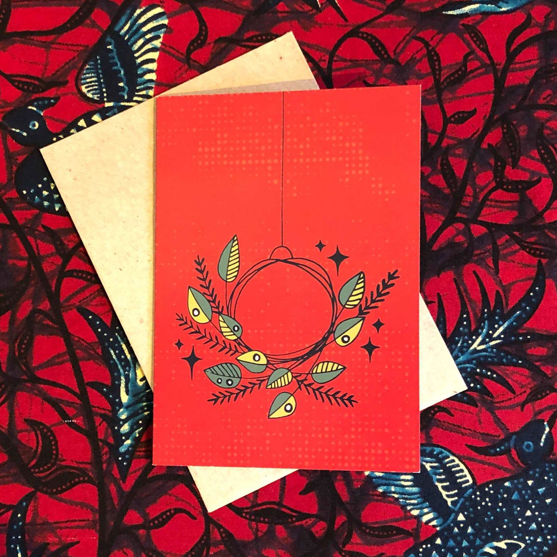 Red colored greeting card with green and yellow wreath