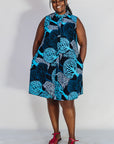 Model wearing sleeveless dress with blue tree print.