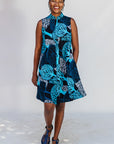 Model wearing sleeveless dress with blue tree print.