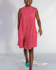 Model wearing red sleeveless dress with white dots.