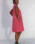 Model wearing red sleeveless dress with white dots.