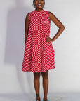 Model wearing red sleeveless dress with white dots.