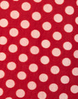 Close up display of red sleeveless dress with white dots, fabric.