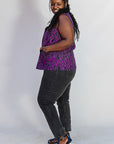 Model wearing purple and black abstract print sleeveless shirt.