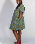 Model wearing blue, yellow, orange and black geometric print dress.
