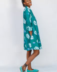 Model wearing teal dress with white cat print.