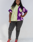Woman wearing a colorful patterned shirt and gray pants on a white background