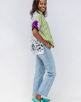 Woman wearing a patterned top, jeans, and turquoise shoes on a white background