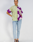 Person wearing a colorful patterned shirt and jeans on a white background