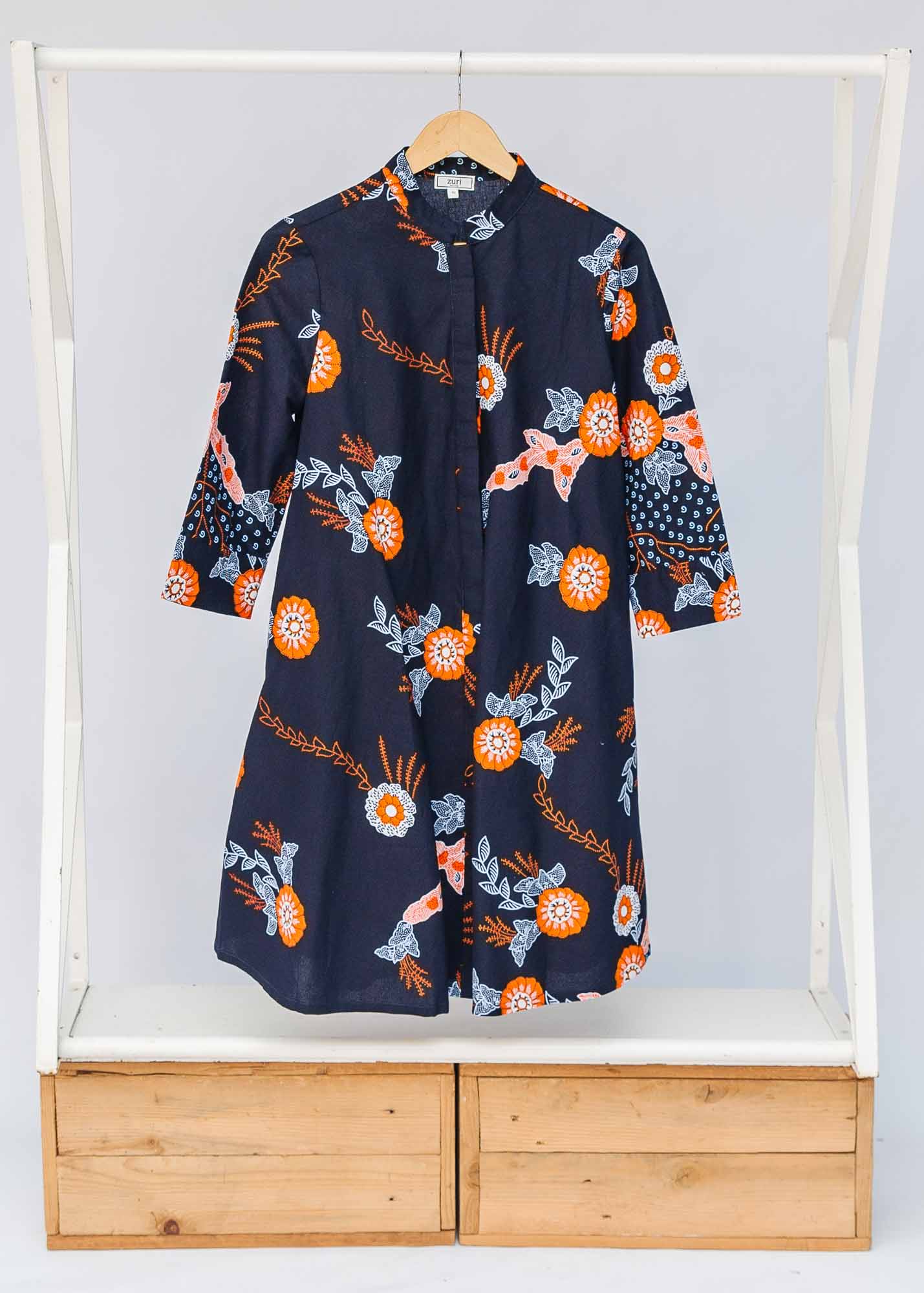Display of black dress with orange, white and brown floral print