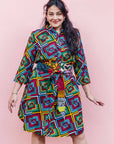 The model is wearing geometric print with rainbow colored dress paired with patchwork belt