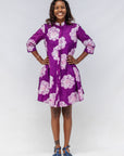 Woman wearing a purple floral dress against a white background