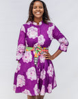 Woman wearing a purple floral dress with a colorful belt that is sold separately on a white background