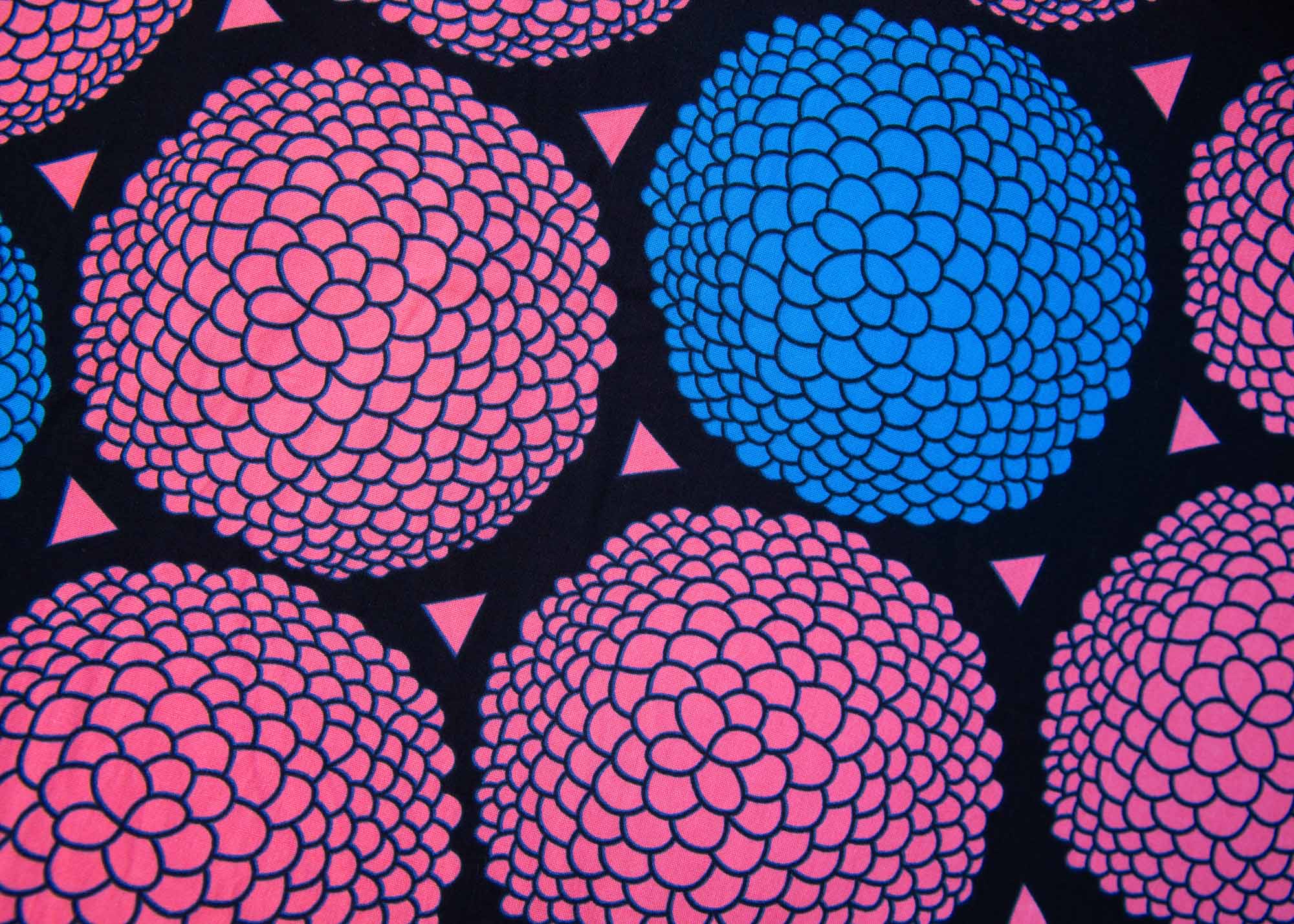 Close up display of coral, blue and black circular print dress