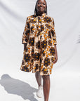 The model is wearing navy, black, off white, yellow flower print dress