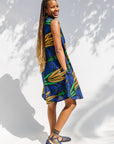 Model wearing blue sleeveless dress with orange and green print.