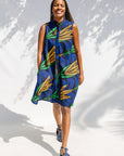 Model wearing blue sleeveless dress with orange and green print.