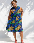 Model wearing blue sleeveless dress with orange and green print.