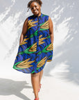 Model wearing blue sleeveless dress with orange and green print.