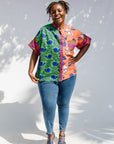 Model wearing green, orange and pink multiprint shirt.
