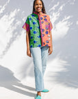 Model wearing green, orange and pink multiprint shirt.