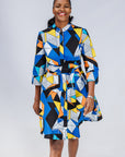 Model wearing blue dress with yellow, black, orange and white geometric print.