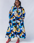 Model wearing blue, black, orange, yellow and white geometric print shirt and pant set.