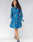 Model wearing blue dress with beige fish print.