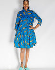 Model wearing blue dress with beige fish print.