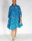 Model wearing blue dress with beige fish print.