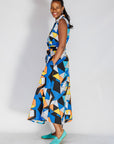 Model wearing blue dress with yellow, black, orange and white geometric print.