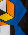 Close up display of blue dress with yellow, black, orange and white geometric print, fabric.