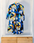 Display of blue dress with yellow, black, orange and white geometric print.
