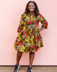 The model is wearing brown, yellow, red and black leaf print dress.