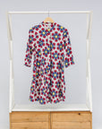 Display of white dress with yellow, red and blue bug print.