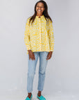 Model wearing yellow long sleeve shirt with white leaf print.