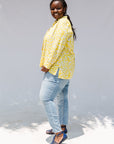 Model wearing yellow long sleeve shirt with white leaf print.