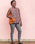 The model is wearing orange, purple, white and black mixed pattern kanga tank