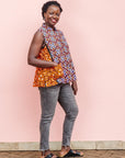 The model is wearing orange, purple, white and black mixed pattern kanga tank