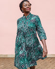 The model is wearing black, green and white geometric print dress