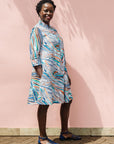 The model is wearing White, black, orange, blue, aqua and brown abstract print dress