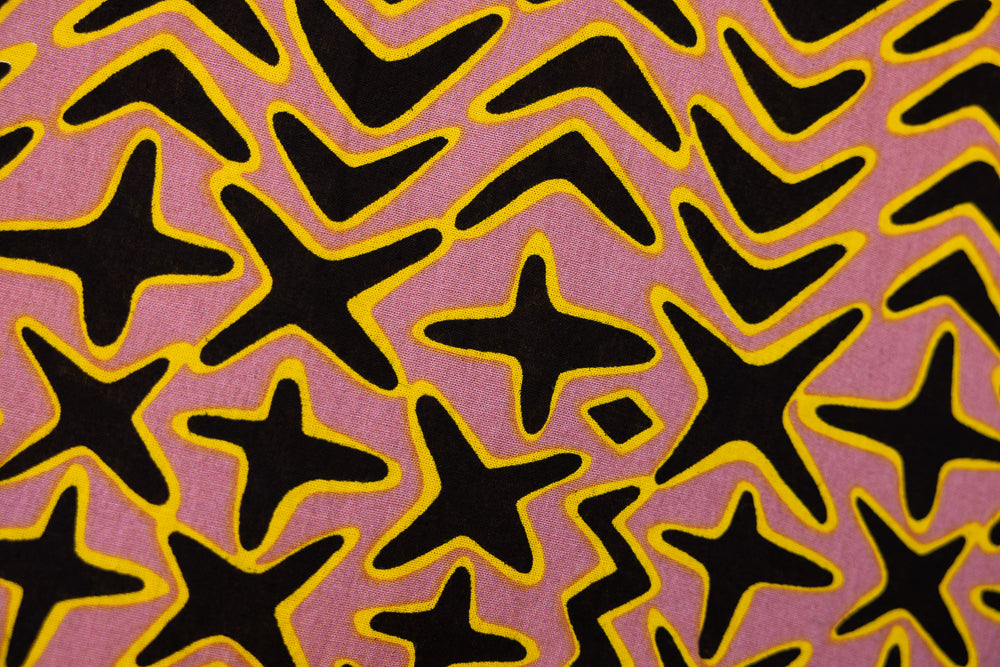 Close up display of beige, yellow and black geometric print dress, fabric.